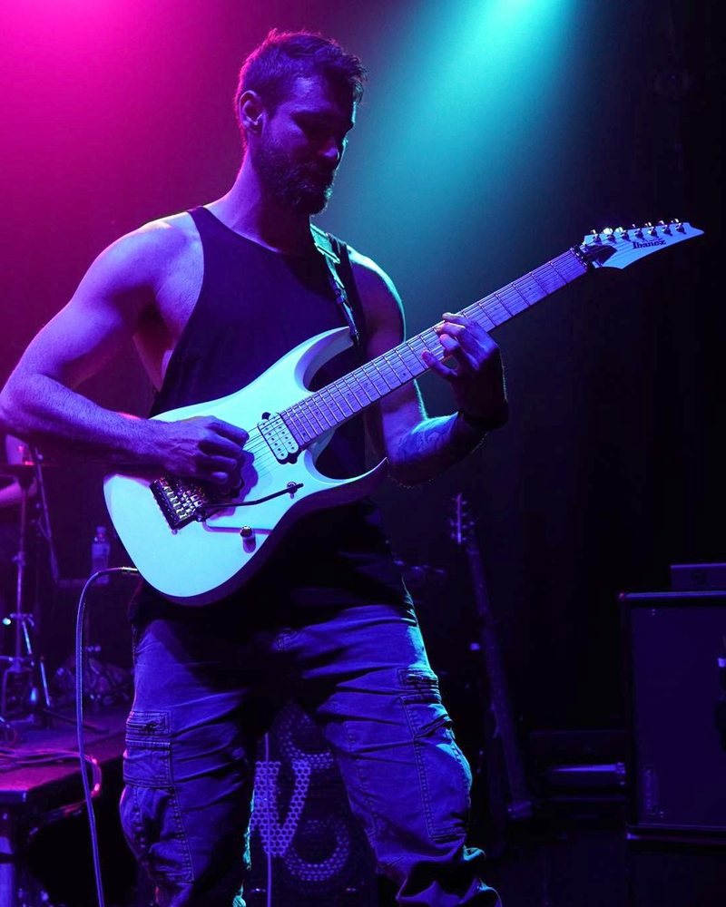 Joe Macedo playing electric guitar on stage